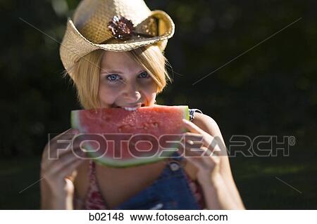 Stock Photo - Portrait of a young woman biting a piece of watermelon. Fotosearch