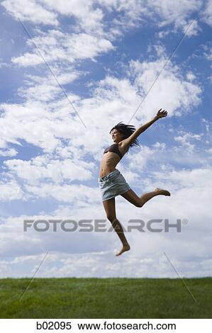 Stock Photography - Profile of a young woman jumping. Fotosearch