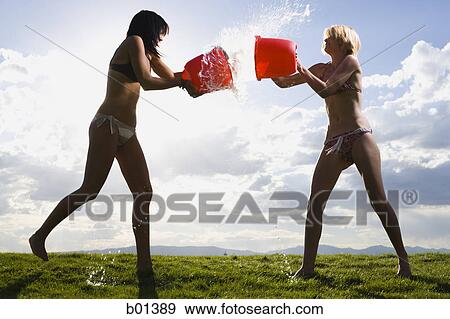 Two young women throwing water at each other View Large Photo Image Stock Photo - Two young women throwing water at each other. Fotosearch
