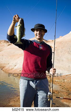 Young man holding a fish with a fishing pole View Large Photo Image Stock Photography - Young man holding a fish with a fishing pole. Fotosearch
