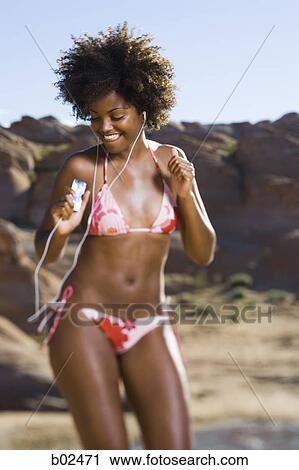 Stock Image - Young woman listening to an MP3 Player and dancing. Fotosearch