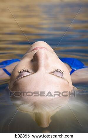 Close-up of a young woman floating on the surface of a lake View Large Photo Image Stock Photography - Close-up of a young woman floating on the surface of a lake. Fotosearch