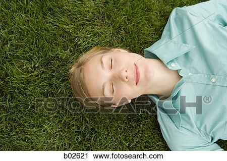 Stock Image - Close-up of a young woman sleeping on grass. Fotosearch