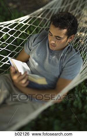 High angle view of a young man reading a book in a hammock View Large Photo Image Stock Photograph - High angle view of a young man reading a book in a hammock. Fotosearch