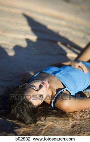 High angle view of a young woman lying on a rock View Large Photo Image Stock Image - High angle view of a young woman lying on a rock. Fotosearch