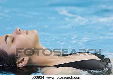 High angle view of a young woman floating in a swimming pool View Large Photo Image Picture - High angle view of a young woman floating in a swimming pool. Fotosearch