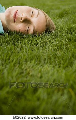 High angle view of a young woman sleeping on grass View Large Photo Image Stock Image - High angle view of a young woman sleeping on grass. Fotosearch