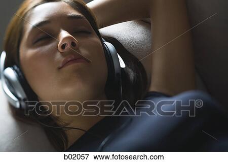 Stock Photo - High angle view of a young woman listening to music on headphones. Fotosearch