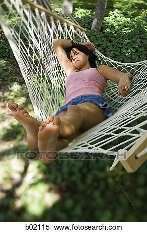 Stock Photography - High angle view of a young woman sleeping in a hammock. Fotosearch