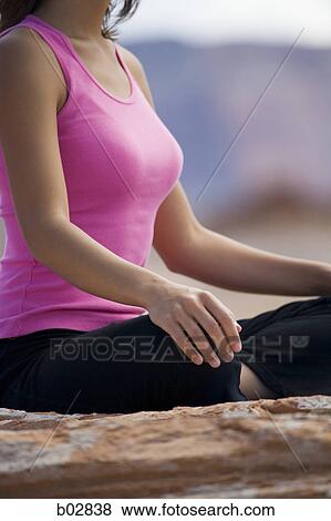 Mid section view of a young woman meditating View Large Photo Image Stock Photo - Mid section view of a young woman meditating. Fotosearch