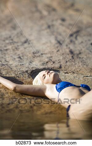 Young woman lying, lake side View Large Photo Image Stock Image - Young woman lying, lake side. Fotosearch