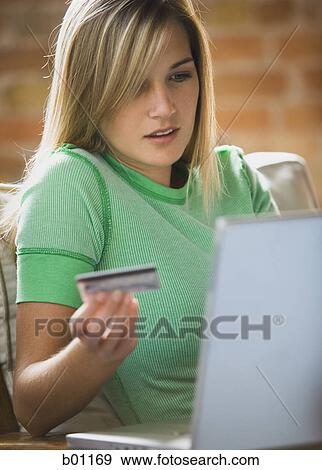 Close-up of a teenage girl holding a credit card sitting in front of a laptop View Large Photo Image Stock Photo - Close-up of a teenage girl holding a credit card sitting in front of a laptop. Fotosearch