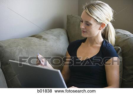 High angle view of a young woman using a laptop and holding a credit card View Large Photo Image Stock Photo - High angle view of a young woman using a laptop and holding a credit card. Fotosearch