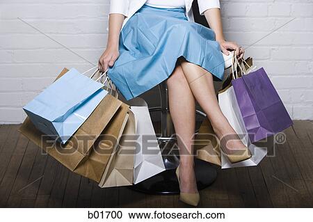 Low section view of a woman sitting on a chair with shopping bags View Large Photo Image Stock Image - Low section view of a woman sitting on a chair with shopping bags. Fotosearch