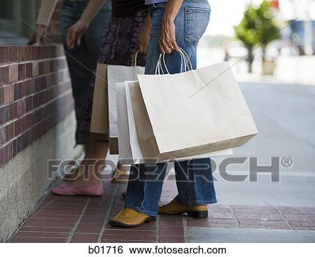 Low section view of three women standing with shopping bags View Large Photo Image Stock Photograph - Low section view of three women standing with shopping bags. Fotosearch