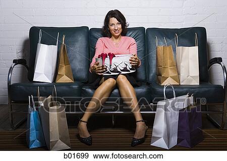 Midi adult woman sitting on a couch with shopping bags View Large Photo Image Stock Photo - Midi adult woman sitting on a couch with shopping bags. Fotosearch