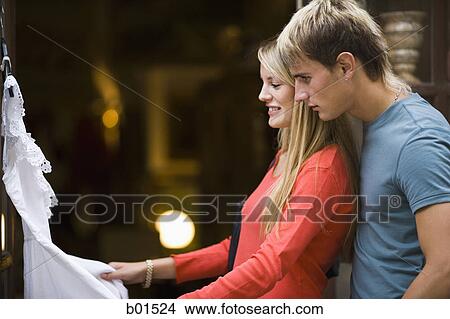 Picture - Portrait of a teenage couple looking at a dress. Fotosearch