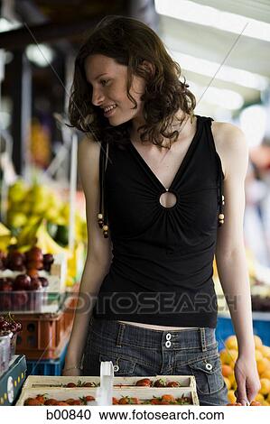 Stock Image - Teenage girl looking at a fruit stand. Fotosearch