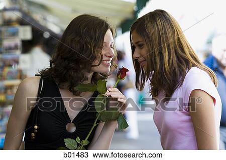 Two teenage girls smelling a rose View Large Photo Image Stock Image - Two teenage girls smelling a rose. Fotosearch
