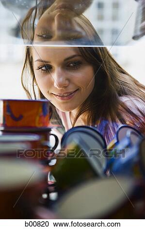 Young woman looking at a window display View Large Photo Image Stock Image - Young woman looking at a window display. Fotosearch