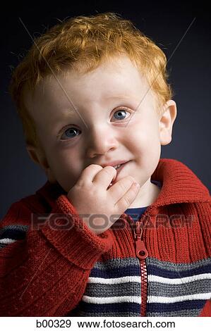 Stock Photo - Close-up of a baby boy with his finger in his mouth. Fotosearch