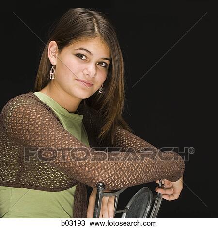 Stock Image - Close-up of a teenage girl sitting on a chair and thinking. Fotosearch