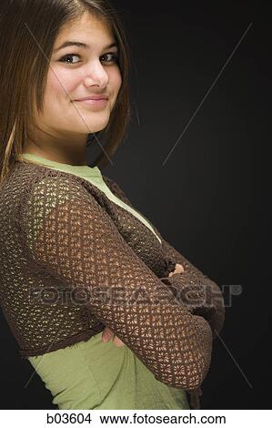 Picture - Low angle view of a young woman holding her hat and jumping. Fotosearch
