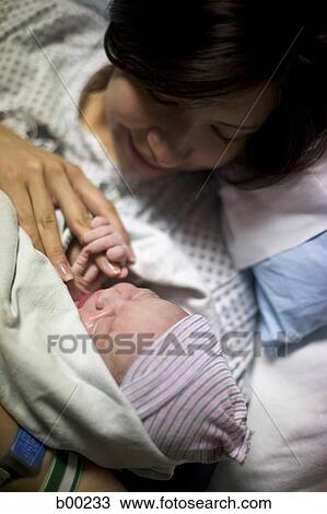 Stock Image - High angle view of a mother loving her newborn baby girl. Fotosearch