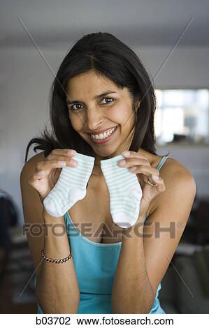 Stock Image - Low angle view of a young woman opening a beer bottle. Fotosearch