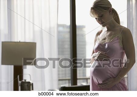 Pregnant woman standing with hand on her belly View Large Photo Image Picture - Pregnant woman standing with hand on her belly. Fotosearch