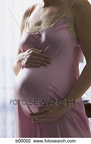Pregnant woman standing with hand on her belly View Large Photo Image Stock Image - Pregnant woman standing with hand on her belly. Fotosearch