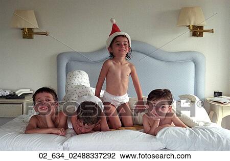 Stock Image - Christmas, Santa Hat, Siblings, Brothers, Sisters, Bed, Resting. Fotosearch
