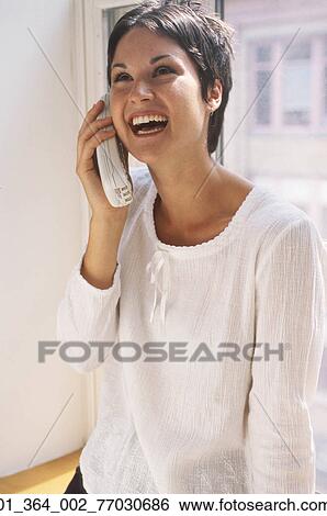 Stock Photograph - Woman, Laughing, Sitting, Seated, Window, Short Hair, Smiling. Fotosearch