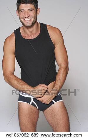 Stock Photo - facing, the, camera, and, smiling, pack, middle, eastern, descent, white, background, vertical, image, underwear, under, 35, years, toned, three, quarter, length, tanned, solo, six, pack, sexy, semi, clothed, relaxed, pants, muscular,. Fotosearch