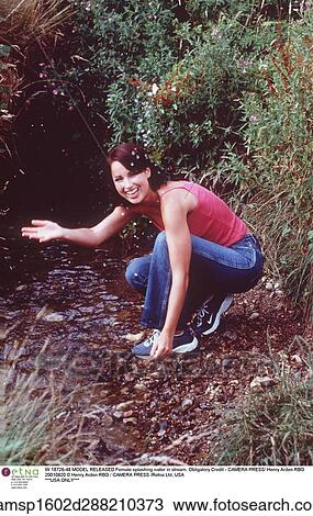 Stock Image - brunette hair, countryside, crouching, european descent, jeans. Fotosearch