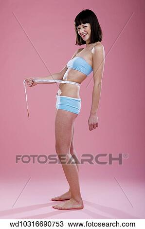 Stock Image - studio, measuring, bra top, weight loss, vertical image. Fotosearch