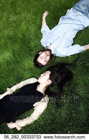 Above view waist up couple lying on grass with their eyes closed and their heads together View Large Photo Image Stock Image - Above view waist up couple lying on grass with their eyes closed and their heads together. Fotosearch