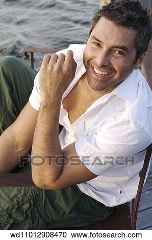 Stock Image - Brunette male wearing a white short sleeved shirt and green combat trousers. Fotosearch