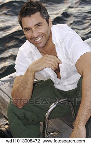 Stock Image - Brunette male wearing a white short sleeved shirt and green combat trousers. Fotosearch