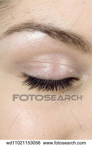 Stock Photograph - Close up of female eye closed with pale biege eyeshadow and black mascara.. Fotosearch