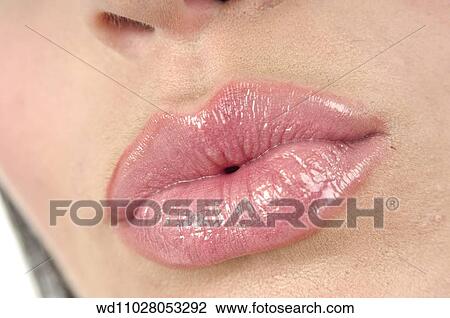 Stock Image - Close up of female wearing pink lipgloss pouting.. Fotosearch