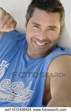 Picture - Cropped image of brunette male wearing a logo print cap sleeved shirt. Fotosearch