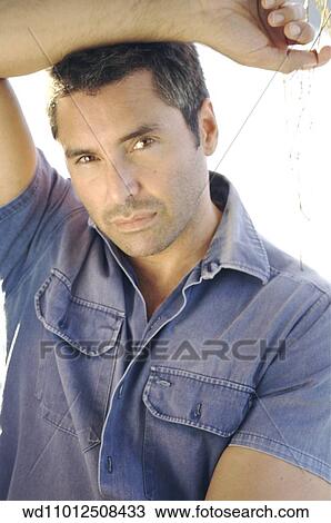 Stock Image - Cropped image of brunette male wearing a blue short sleeved shirt. Fotosearch