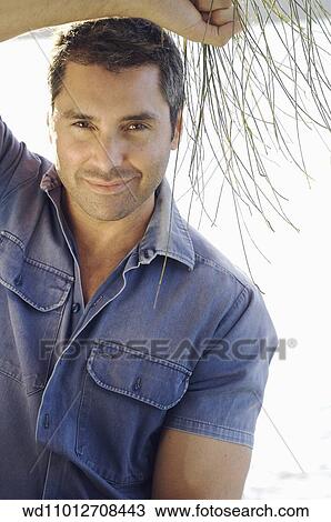 Stock Image - Cropped image of brunette male wearing a blue short sleeved shirt". Fotosearch