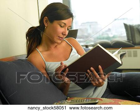 Ethnic Girl wearing a blue tank top sits in her apartment enjoying a book for relaxation. View Large Photo Image Stock Image - Ethnic Girl wearing a blue tank top sits in her apartment enjoying a book for relaxation.. Fotosearch