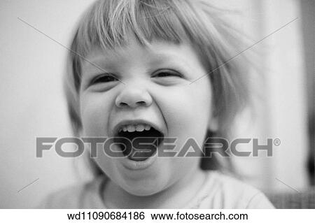 Stock Photograph - Female child looking straight to camera and with her mouth open. Fotosearch