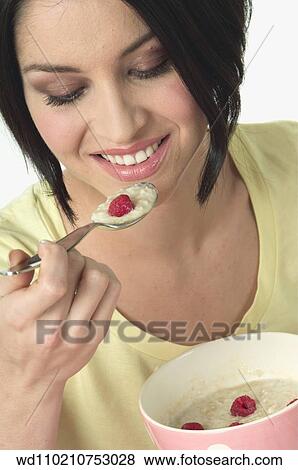 Female with straight chin length brunette hair wearing pale yellow t shirt eating porridge with rasberries from pink and white spotted bowl View Large Photo Image Stock Photo - Female with straight chin length brunette hair wearing pale yellow t shirt eating porridge with rasberries from pink and white spotted bowl. Fotosearch