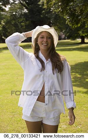 Half length front view young woman long blonde hair walking in a park looking at camera smiling holding cowboy hat with hand on her head View Large Photo Image Stock Image - Half length front view young woman long blonde hair walking in a park looking at camera smiling holding cowboy hat with hand on her head. Fotosearch