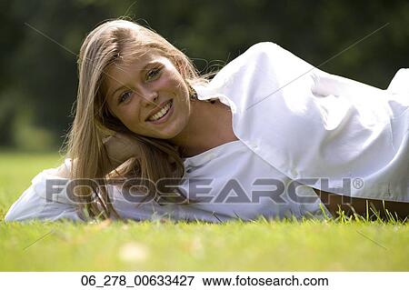 Half length front view young woman long blonde hair lying on grass leaning on elbow looking at camera smiling View Large Photo Image Stock Photo - Half length front view young woman long blonde hair lying on grass leaning on elbow looking at camera smiling. Fotosearch