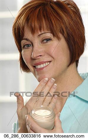 Head and shoulders front view portrait woman rubbing moisturiser into her face looking at camera smiling View Large Photo Image Stock Photograph - Head and shoulders front view portrait woman rubbing moisturiser into her face looking at camera smiling. Fotosearch